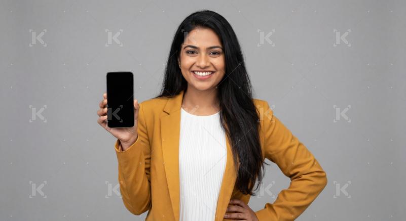 Young indian woman holding smartphone standing on isolated background