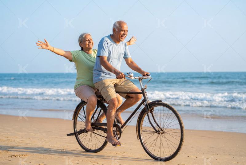 Happy indian mature couple enjoying on cycle together on beach