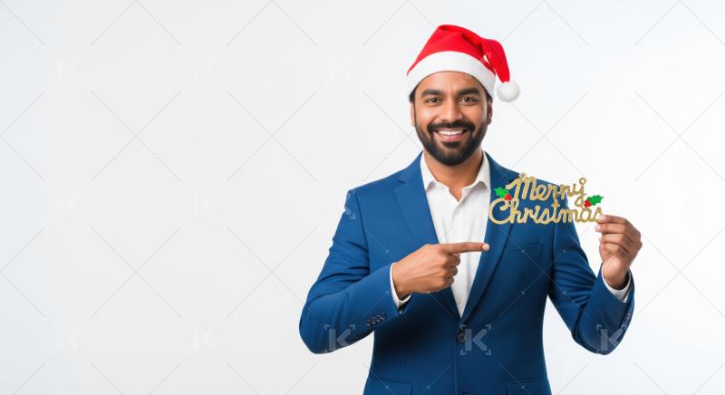 Happy man pointing to a festive Merry Christmas sign.