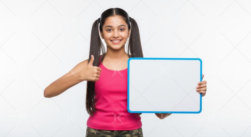 Smiling young Indian girl holds whiteboard, showing thumbs up.