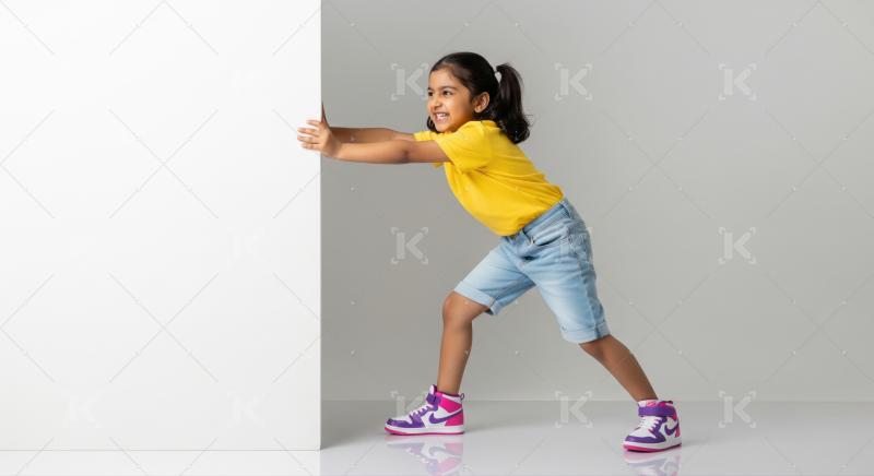 Smiling Indian girl energetically pushing a plain white surface.