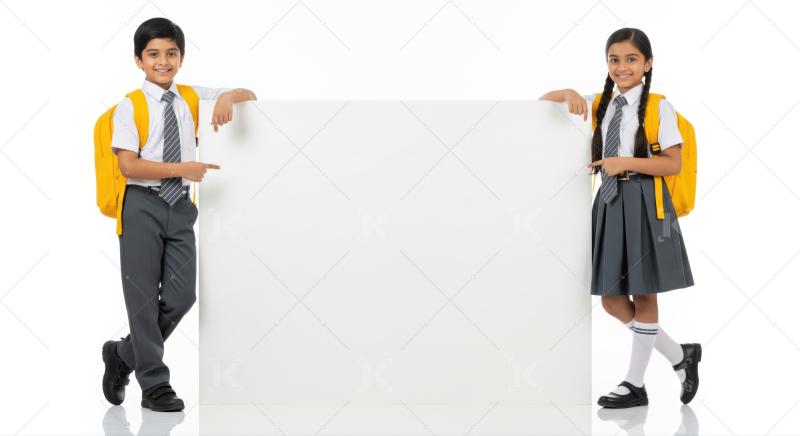 Smiling Indian students with backpacks pointing to a blank sign.