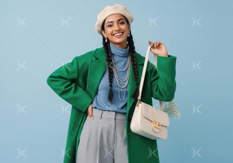 Smiling Indian woman in stylish green coat and beige beret