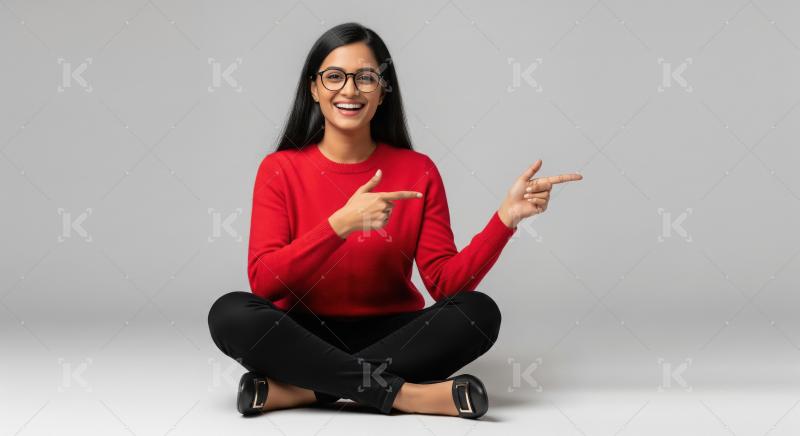 Happy Indian Woman Smiling and Pointing Sideways on Grey