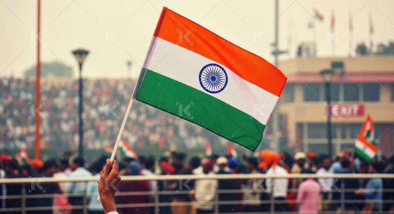 Hand holding India's flag amidst a patriotic, cheering crowd.