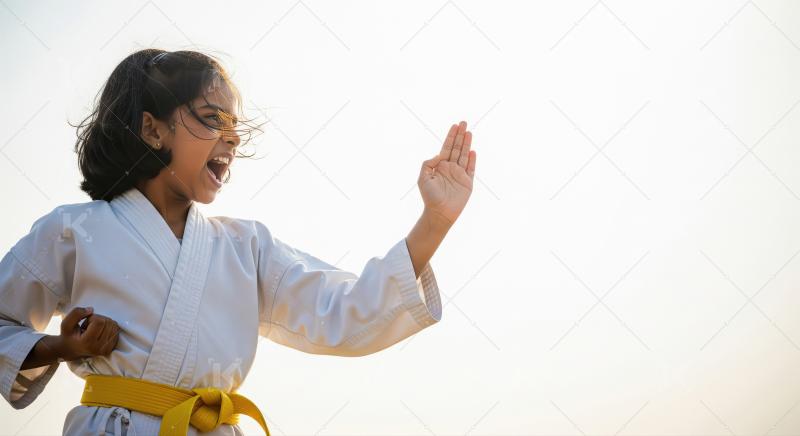 Energetic child practicing karate outdoors with a yellow belt