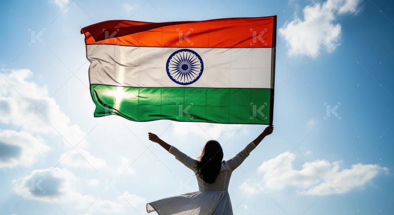 Woman proudly holds Indian flag against bright blue sky.