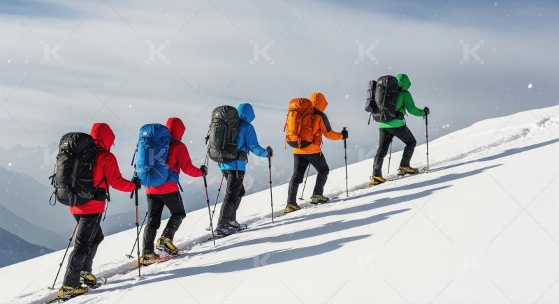 Winter hikers ascending snowy mountain with snowshoes and backpa