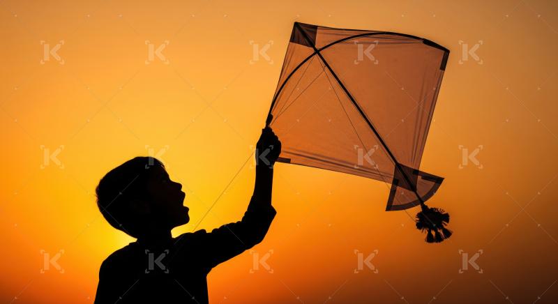Happy child's silhouette against a vibrant, warm sunset sky.