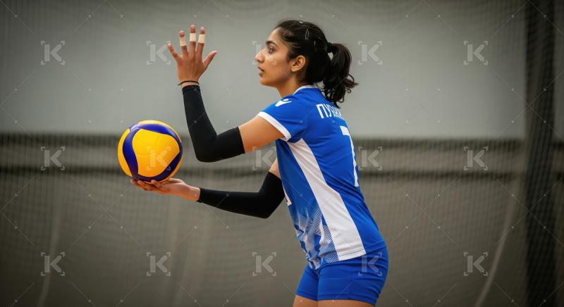 Dedicated female volleyball player practicing her serve indoors.