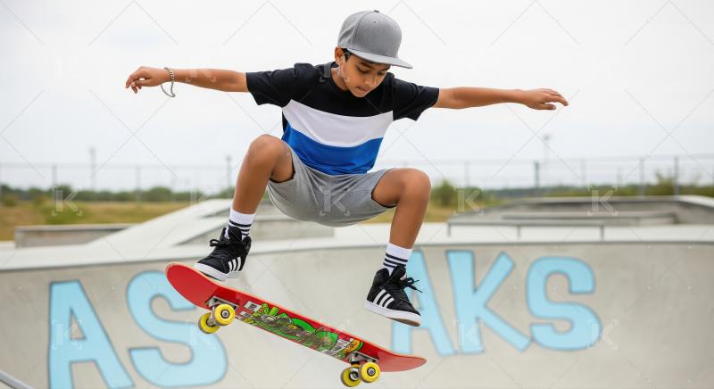 Young Boy Performs Skateboard Trick Mid-Air at Outdoor Skatepark
