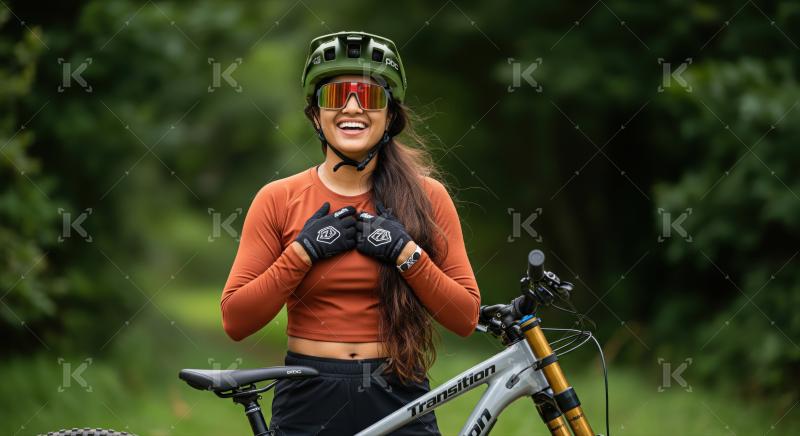 Happy female mountain biker poses with her bike in nature.