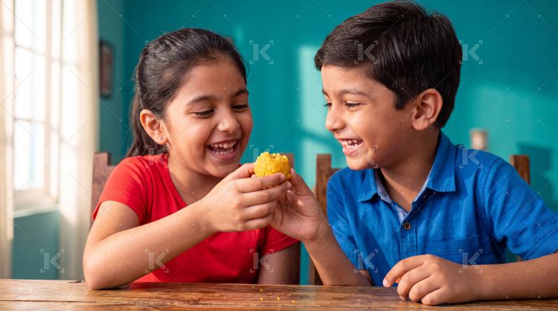 Happy indian brother and sister enjoying food together at home