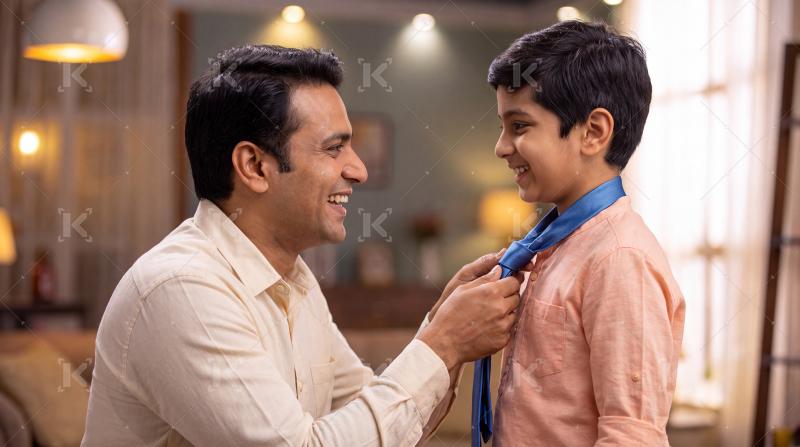 Happy Indian father is putting a tie on his son.