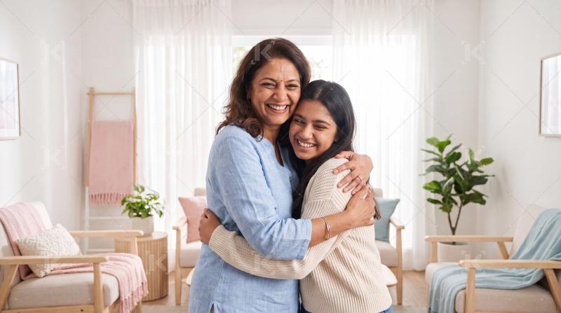 Young indian daughter and mother hugging together at home