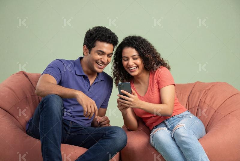 Young indian couple using smartphone together at home