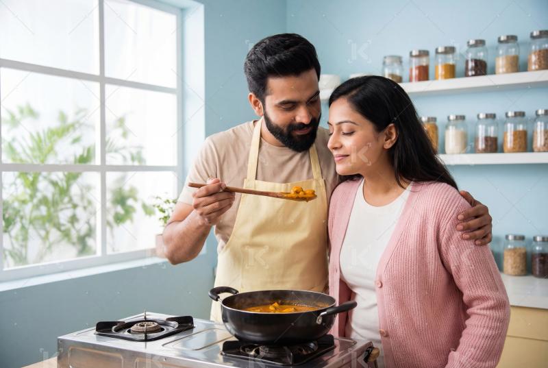 Young indian couple cooking together in kitchen
