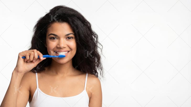 Young indian woman brushing teeth standing on white background