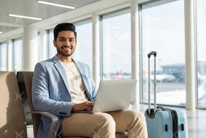 Young indian man using laptop sitting at airport
