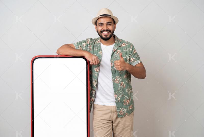 Young indian man standing with big mobile screen on isolated background