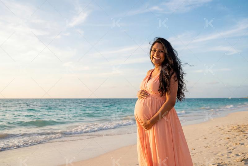 Young indian pregnant woman standing at beach