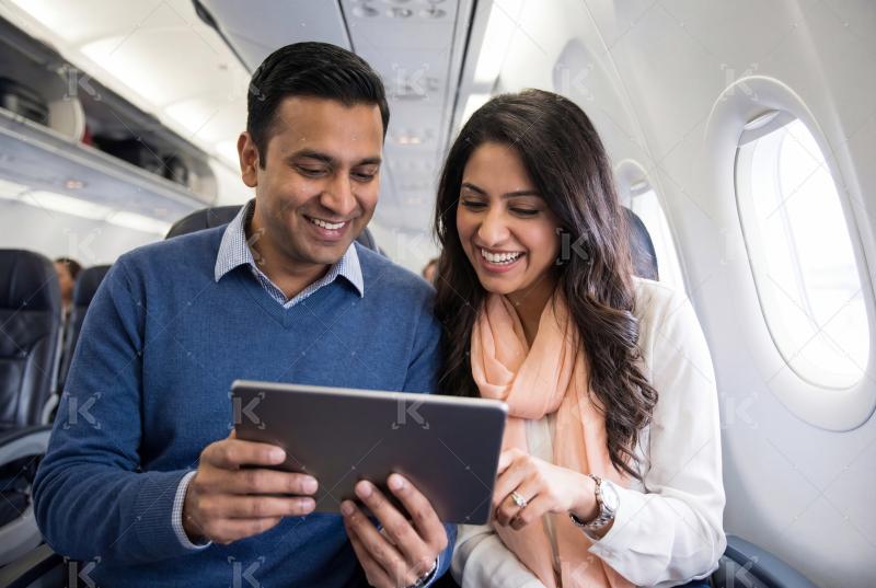 Young indian couple using tablet in the plane