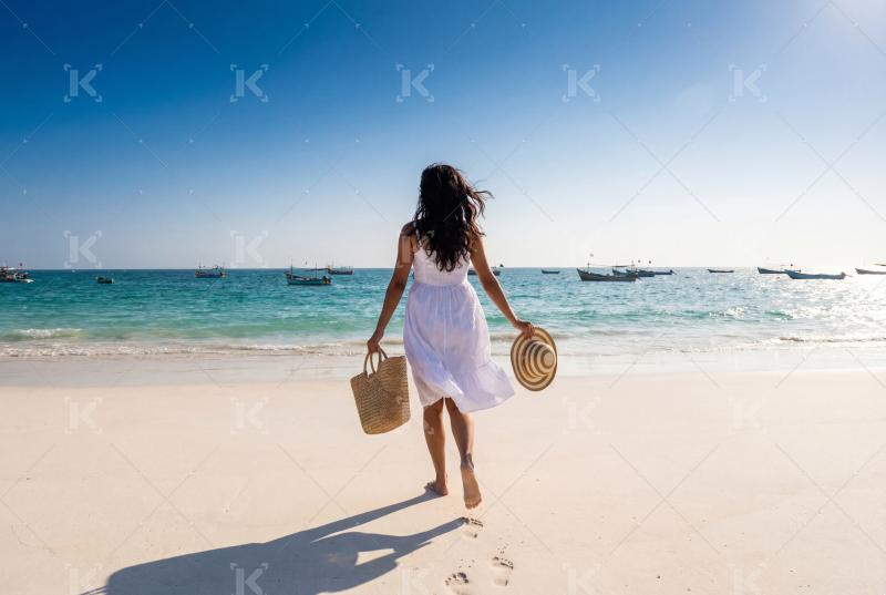 Young beautiful woman walking on sea beach