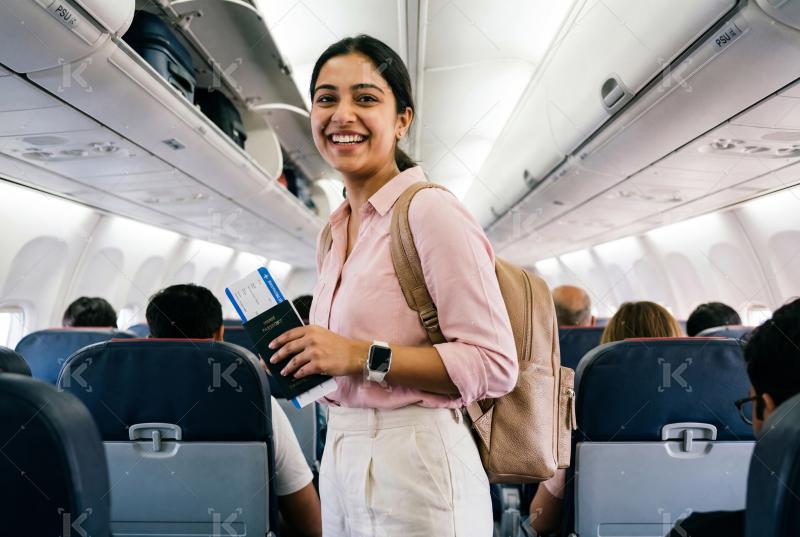 Young indian woman holding ticket and smartphone standing at airport