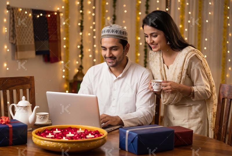 A happy Muslim couple sitting at home using a laptop and credit