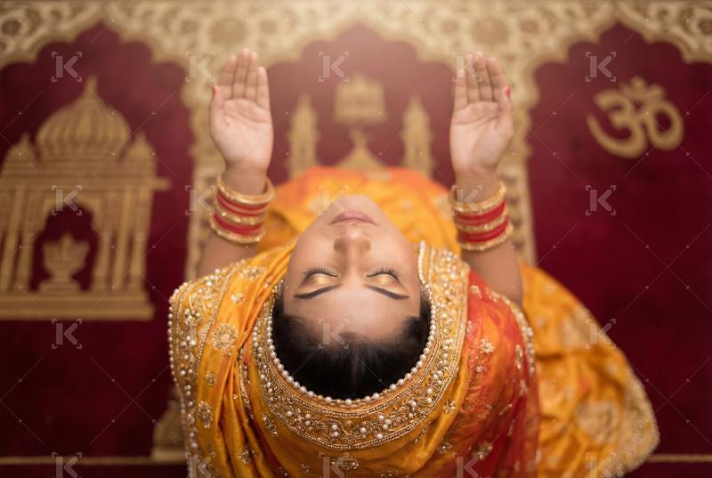 A Hindu woman in traditional attire raising her hands in prayer