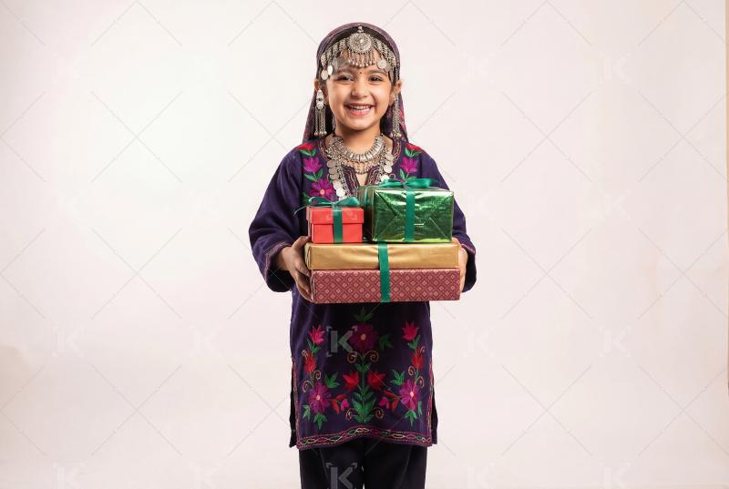 A smiling little girl in traditional ethnic attire holding sever