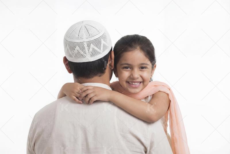 A joyful little girl hugging her father from behind, smiling war