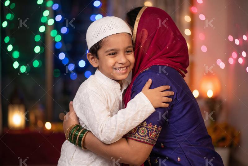 A smiling young boy in traditional attire warmly hugging his mot