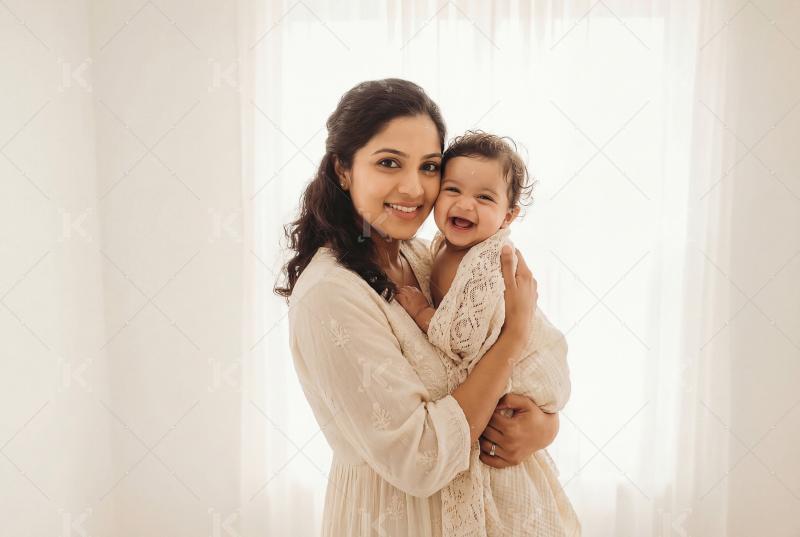 Young indian mother holding cute little baby standing at home