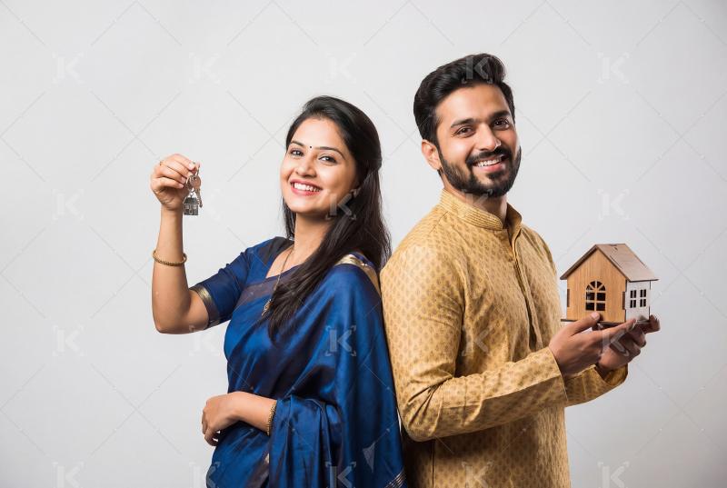 Young indian couple holding home model and keys standing togethe
