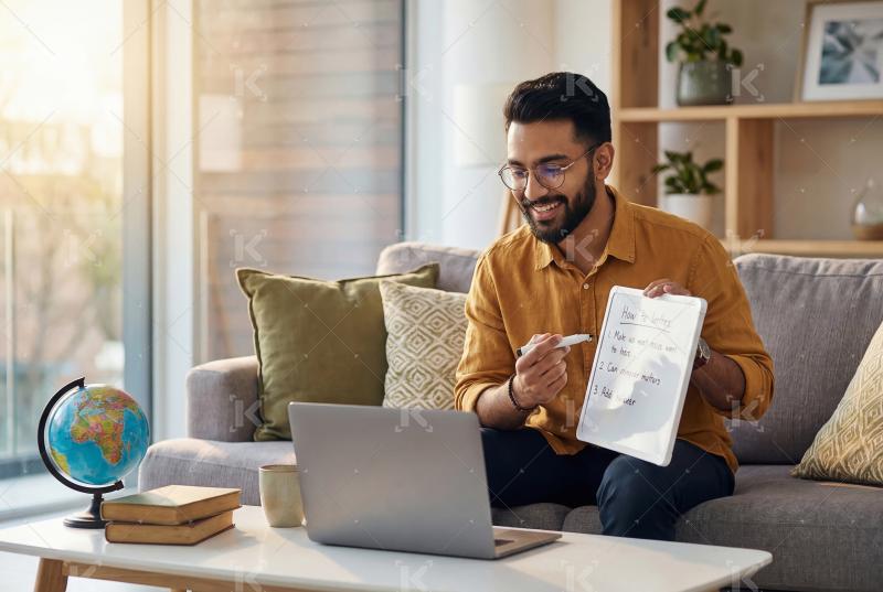 Young indian man working on laptop sitting at home
