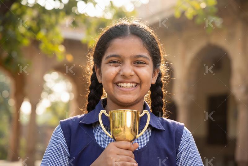 Happy indian villager school girl holding trophy