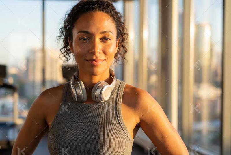 Young indian woman standing with headphone at gym