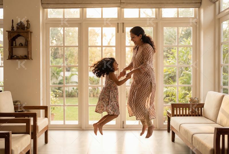 Joyful indian mother and daughter playfully jumping and dancing
