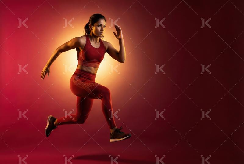 A determined female athlete sprints dynamically against a vibran