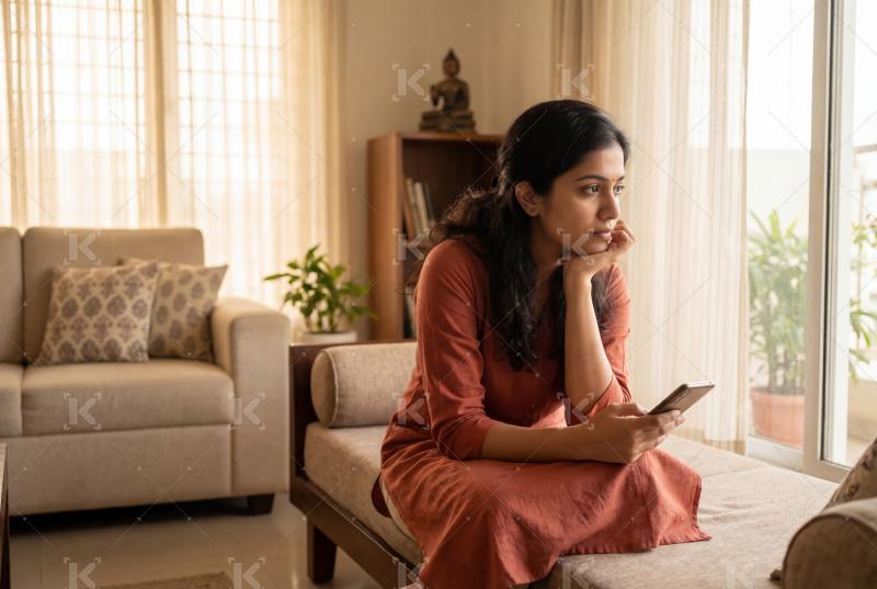 Indian woman sitting in home alone and thinking some while holdi