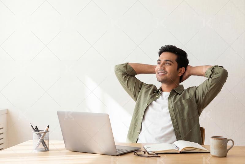 A relaxed professional leans back at his desk, reflecting with s