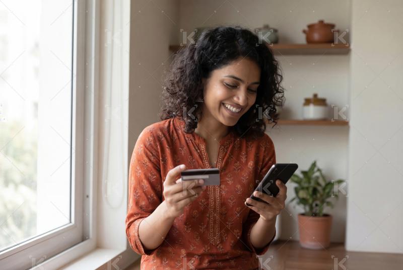 A happy woman using her smartphone and credit card to make an on