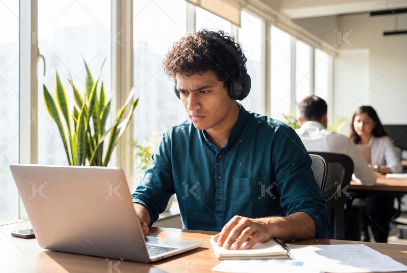 A focused young professional works intently on a laptop in a mod