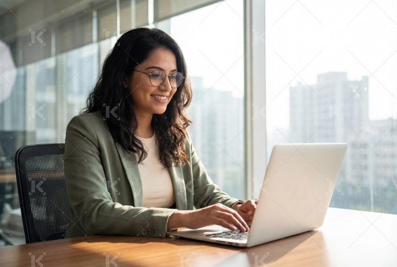 Happy young indian business woman working on laptop