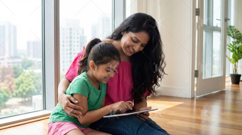 Happy indian mother and daughter using tablet together at home
