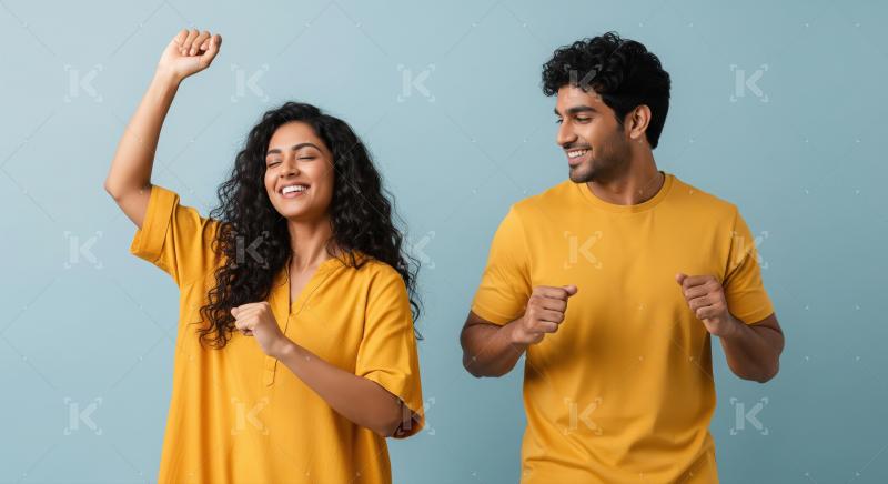 A young couple stands indoors, dancing with raised arms and smil