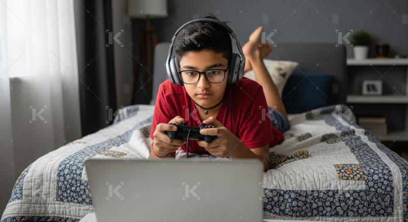 Focused young boy playing video games on laptop at home