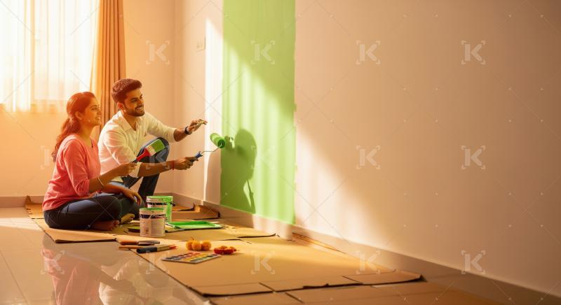 Happy Indian couple painting new home with vibrant green.