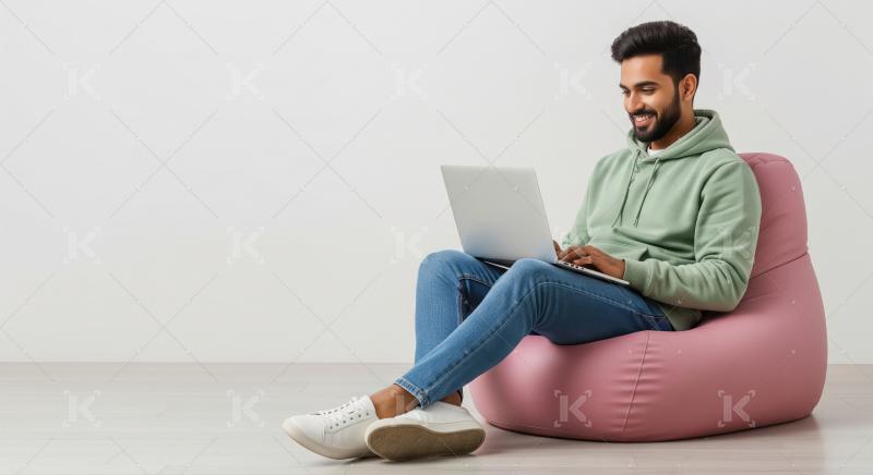 Young Man Happily Working on Laptop from Comfortable Beanbag
